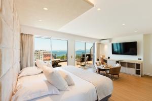 a bedroom with a large white bed and a balcony at Hôtel Hélios in Juan-les-Pins