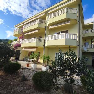 a yellow building with white balconies and plants at Apartments Glavaš in Makarska