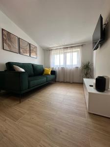 a living room with a green couch and a television at Apartmani M&L in Medulin