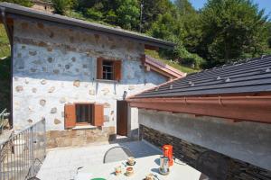 a stone house with a table on a patio at Baita Michele con Terrazzo e bellissima Vista Lago x 4 Persone in Aurano
