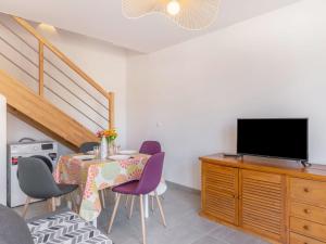 ein Esszimmer mit einem Tisch mit lila Stühlen und einem TV in der Unterkunft Apartment SC G01 by Interhome in Mimizan
