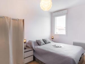 ein weißes Schlafzimmer mit einem Bett und einem Fenster in der Unterkunft Apartment SC G01 by Interhome in Mimizan