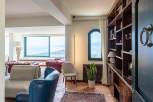 Una sala de estar con un sofá y sillas y ventanas. en Villa Marta Luxury Sea View and Spa, en Taormina
