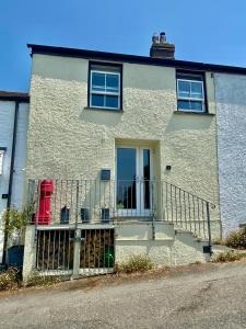 a white house with a balcony with two red chairs at Frogmore Corner in Tregoney