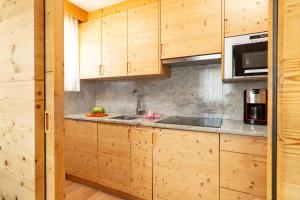 a kitchen with wooden cabinets and a sink at Ciasa Sopl&agrave; in San Cassiano