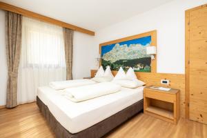 a bedroom with a large bed with white pillows at Ciasa Sopl&agrave; in San Cassiano