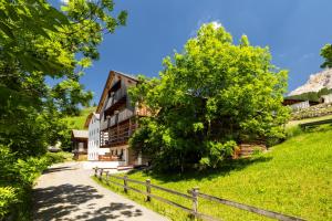 a building with a tree next to a fence at Ciasa Sopl&agrave; in San Cassiano