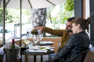 Um homem a servir um copo de vinho a uma mulher à mesa. em Hotel Montefiore em Tel Aviv