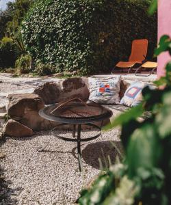 a fire pit in a gravel yard with two chairs at Nativo Natureza Pink Wood Cabin in Cela