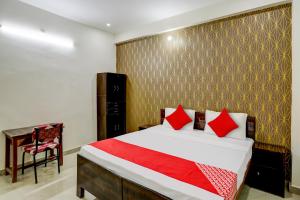 a bedroom with a bed with red pillows and a desk at Hotel O The Raghav Villa in Prayagraj