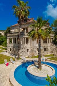 a large stone house with a swimming pool and palm trees at Boutique Villa Filaus in Dubrovnik
