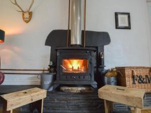 ein Kamin in einem Wohnzimmer mit zwei Holztischen in der Unterkunft Holiday Home Easdale Cottage by Interhome in Oban