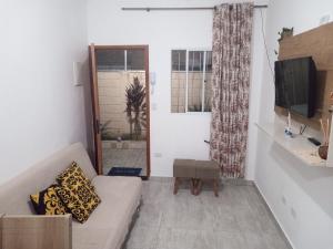 un salon avec un canapé et une télévision dans l'établissement Casa de cond com piscina e churrasqueira particular, à Itanhaém