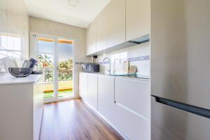 a kitchen with white cabinets and a large window at Home Olimpo Torre del Mar in Torre del Mar