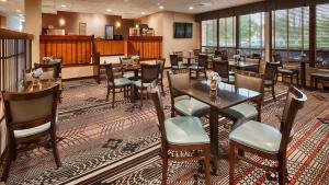 a dining room with tables and chairs and windows at Days Inn by Wyndham Englewood Dayton Airport in Dayton