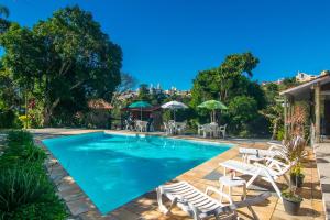 ein Swimmingpool mit weißen Stühlen und Sonnenschirmen in der Unterkunft Hospedagem Vila Rica - 500m do centro de Cunha SP in Cunha