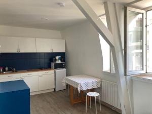 a kitchen with white cabinets and a table and a window at Les Bains de Mers in Mers-les-Bains