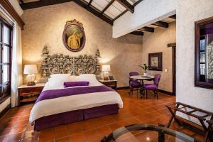 アンティグア・グアテマラにあるLas Cruces Boutique Hotelの大きなベッドとテーブルのある寝室