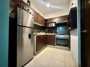La cuisine est équipée d'un réfrigérateur en acier inoxydable et de placards bruns. dans l'établissement Casa en el corazón de Playa del Carmen, à Playa del Carmen