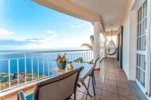 a balcony with a table and chairs and the ocean at Casa Serena Apartments in Arco da Calheta