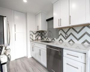 a kitchen with white cabinets and a geometric wall at Upper West Newport in Newport Beach +8 photos