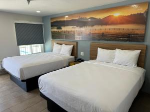 a hotel room with two beds and a painting on the wall at Days-Inn by Wyndham Bakersfield in Bakersfield +33 photos