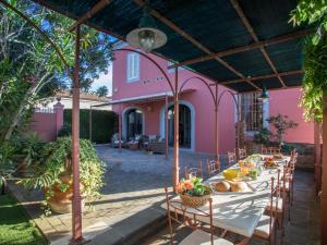 a long table in a courtyard with a pink house at Villa La Veduta by Interhome in Molino Mazzetti