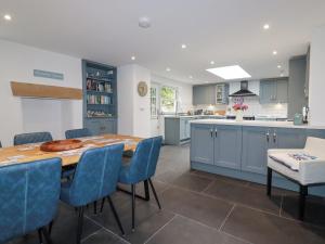 a kitchen with a wooden table and blue chairs at Dale Cottage in Crantock
