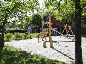 a playground with a wooden swing set in a yard at Holiday Home 4-persoons bos-2 by Interhome in Dalfsen