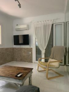 a living room with a table and a chair and a tv at Dori's Seaside Apartment in Athens