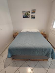 ein Schlafzimmer mit einem Bett mit blauer Bettdecke in der Unterkunft Perdika Sunset in Pérdika