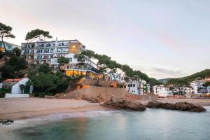 a group of houses on a beach with a body of water at Hotel Hostalillo by Escampa Hotels in Tamariu
