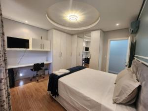 a bedroom with a large white bed and a desk at Pousada Behling Haus in Pomerode