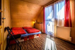 a room with a bed with red pillows and a window at chatyliptov v srdci LIPTOVA in Liptovský Trnovec