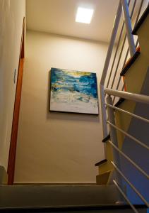 een schilderij aan een muur naast een trap bij Serena Beach Triplex in Caraguatatuba