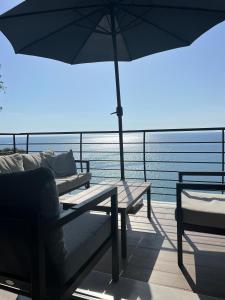 a balcony with two benches and an umbrella at The Yacht House in Agios Ioannis Pelio