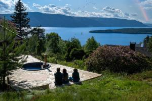 three people sitting on a deck looking at a lake at Mountain & Lake Haven & Close to Oslo in Stange +19 photos