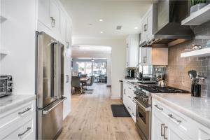 a kitchen with white cabinets and stainless steel appliances at Upper West Newport in Newport Beach