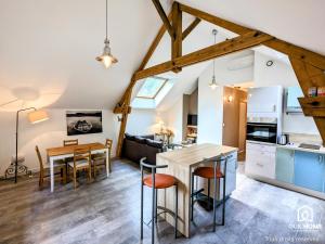 a kitchen and dining room in a loft with wooden beams at Les Charmes - Climatisation - Terrasse - Nature in Boigny-sur Bionne