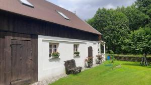 a building with two windows and a bench in a yard at Siedlisko Pod Dębem in Udzierz
