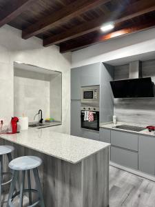 Una cocina con encimera y taburetes. en Casa Vacacional en Louro, en Muros