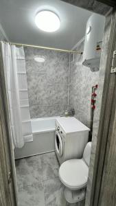 a bathroom with a toilet and a sink and a tub at Двухкомнатная квартира в центре города Сейфуллина 33 in Balqash