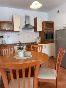 a kitchen with a wooden table with chairs and a kitchen with a refrigerator at APP Mirela 3 in Novi Vinodolski