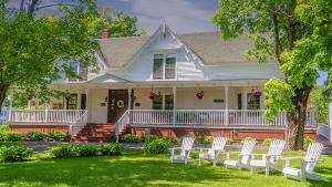 a white house with white chairs on the lawn at Gillespie House Inn in Parrsboro