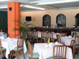 a dining room with white tables and wooden chairs at Novotel De Poza Rica in Poza Rica de Hidalgo