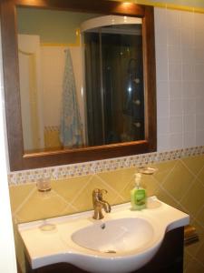 ein Badezimmer mit einem Waschbecken mit einem Spiegel und einem Seifenspender in der Unterkunft Apartamentos rurales Casa Rosi in Ranón