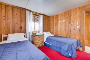 two beds in a room with wooden walls at Fire Pit and Community Perks Gouldsboro Cabin! in Gouldsboro +18 photos