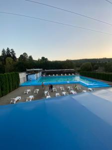 an overhead view of a large swimming pool with white chairs at Pensiunea Hyperion Cormaia in Sângeorz-Băi