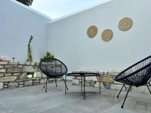two chairs and a table in front of a wall at Bamboo House Syros 2 in Ermoupoli
