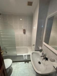 a bathroom with a sink and a tub and a toilet at Hotel Xacobeo in Outeiro